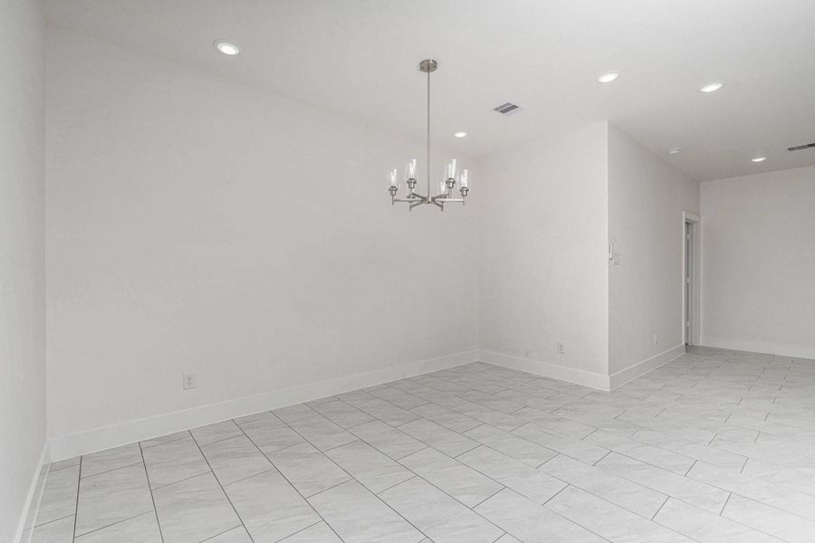 This room features a modern, open layout with light tile flooring and recessed lighting. It's complemented by a stylish chandelier, offering a bright and spacious feel, perfect for dining or living space. This room features a modern, open layout with light tile flooring and recessed lighting. It's complemented by a stylish chandelier, offering a bright and spacious feel, perfect for dining or living space.