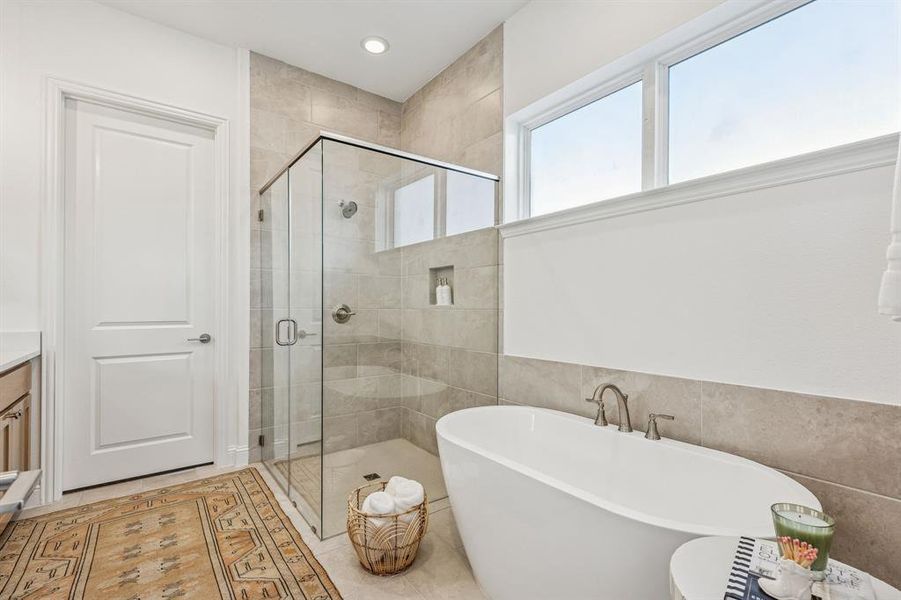 Bathroom featuring a stall shower, a freestanding tub, vanity, tile walls, and recessed lighting