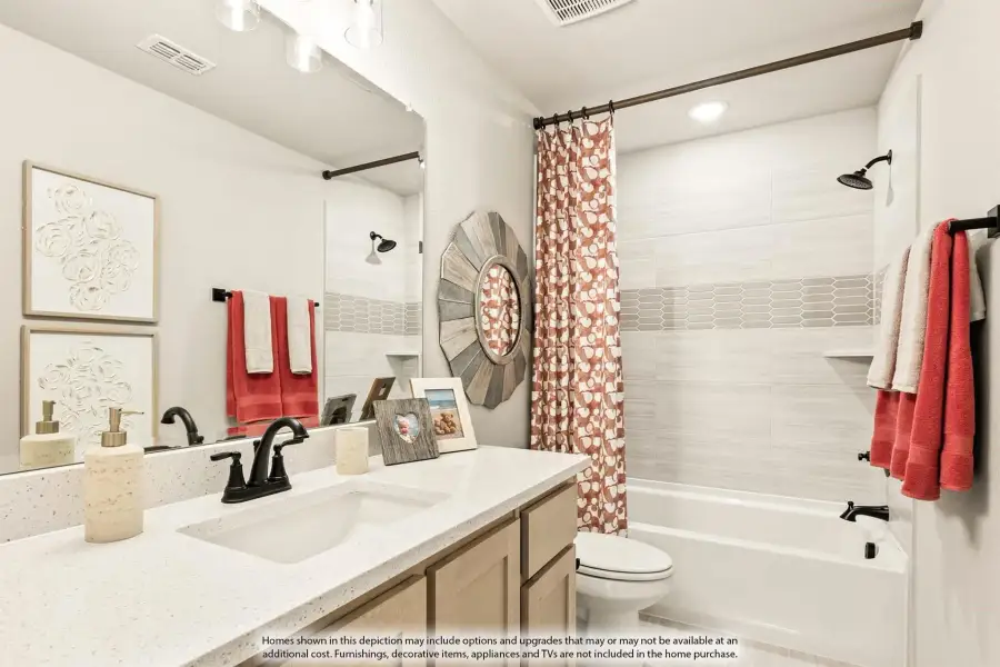 Bathroom with white quartz countertop, single sink, tub-shower combo with tiled surround, and toilet