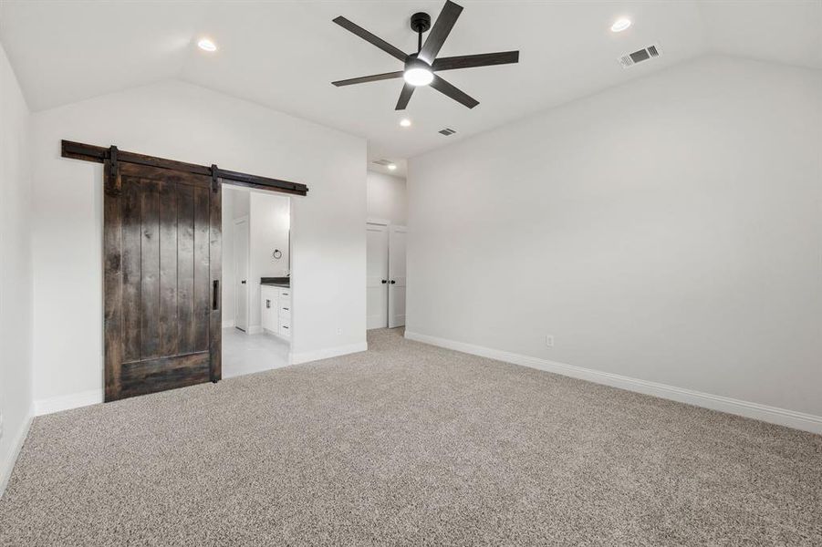 Unfurnished bedroom with lofted ceiling, light carpet, ensuite bath, ceiling fan, and recessed lighting