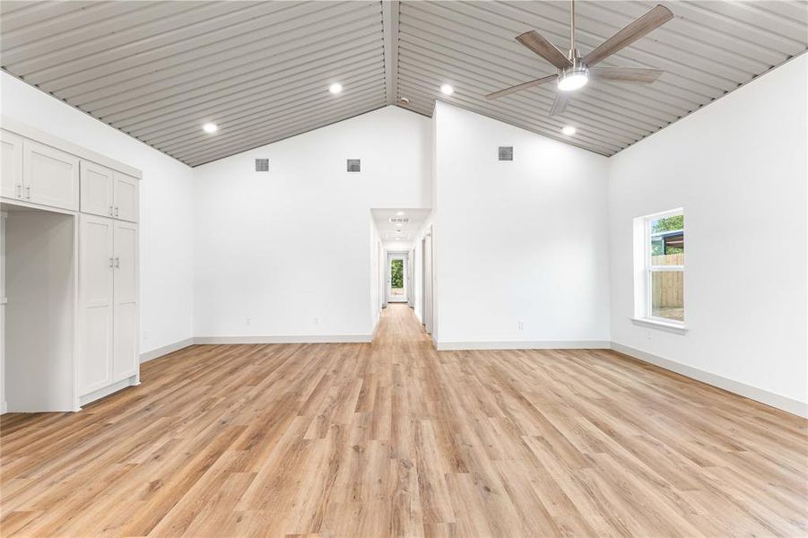 Unfurnished living room featuring high vaulted ceiling, a ceiling fan, light wood-style flooring, recessed lighting, and baseboards Unfurnished living room featuring high vaulted ceiling, a ceiling fan, light wood-style flooring, recessed lighting, and baseboards