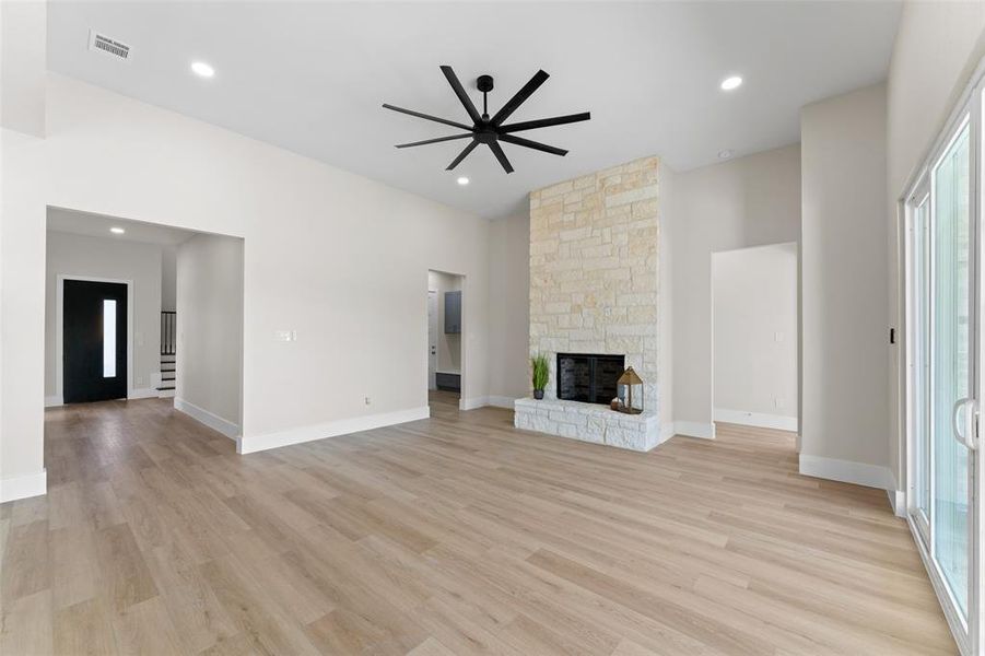 Unfurnished living room with ceiling fan, a fireplace, light wood-type flooring, and recessed lighting Unfurnished living room with ceiling fan, a fireplace, light wood-type flooring, and recessed lighting