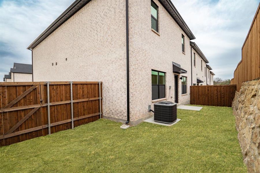 Back elevation and fully fenced yard. The grass color has been virtually enhanced to show what it may look like in spring.