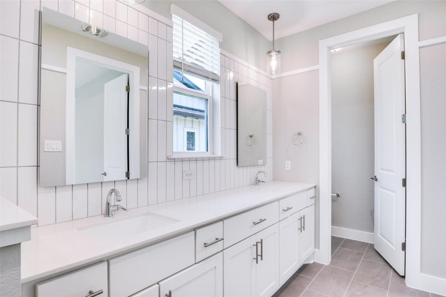 Bathroom featuring decorative backsplash, vanity, and tile patterned flooring