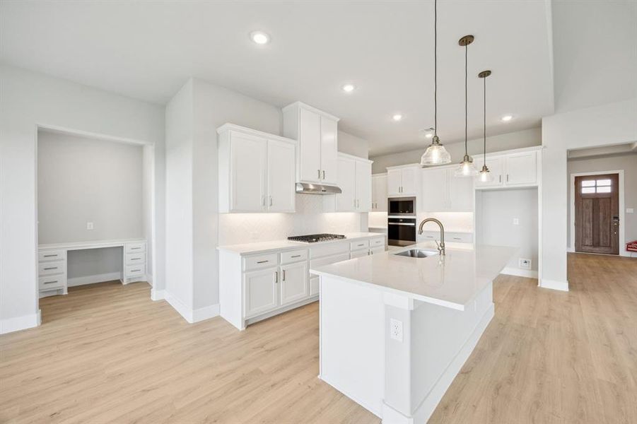 Kitchen featuring a kitchen island with sink, decorative backsplash, decorative light fixtures, white cabinetry, and recessed lighting