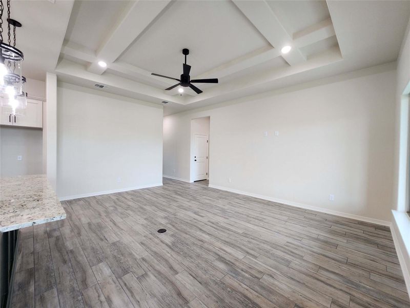 Spacious living area featuring wood-finish flooring, a coffered ceiling with recessed lighting and a ceiling fan, and light-toned walls