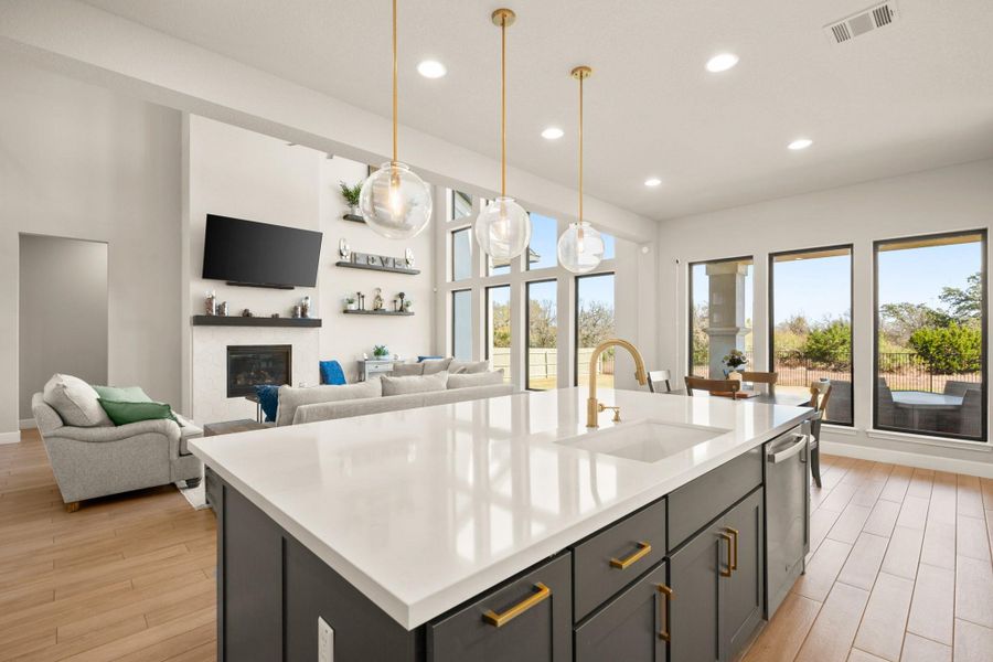 Kitchen with pendant lighting, recessed lighting, light wood finished floors, a glass covered fireplace, and a center island with sink Kitchen with pendant lighting, recessed lighting, light wood finished floors, a glass covered fireplace, and a center island with sink