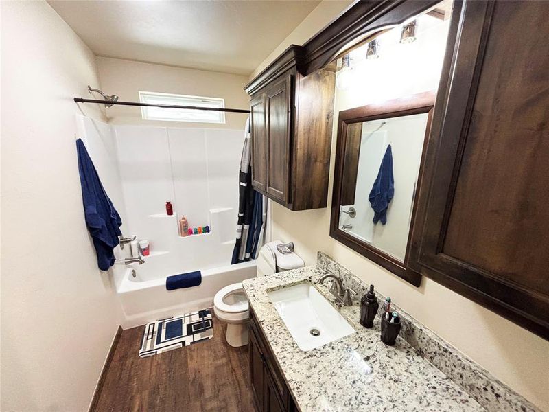 Bathroom featuring vanity, dark wood-type flooring, and shower / tub combo with curtain Bathroom featuring vanity, dark wood-type flooring, and shower / tub combo with curtain