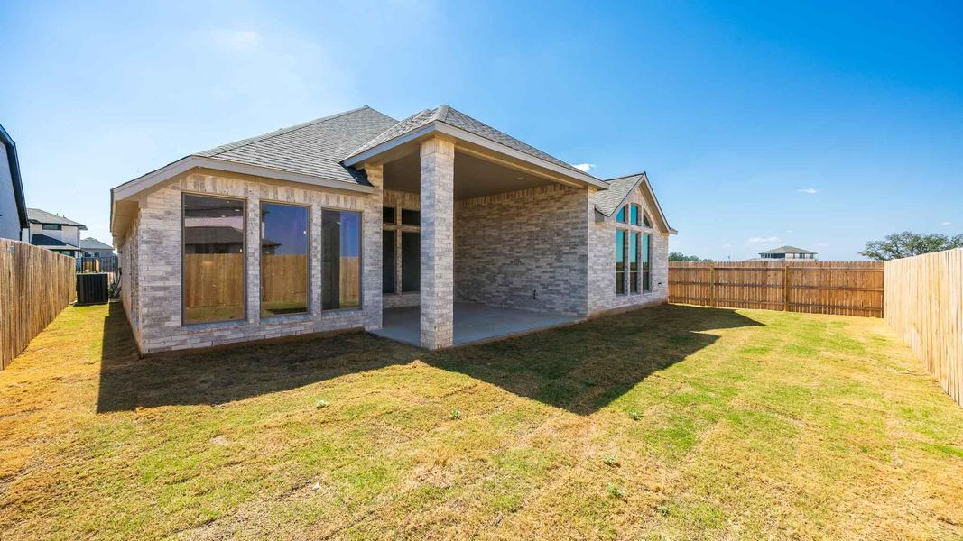 Rear view of property featuring a patio area, a fenced backyard, brick siding, and roof with shingles