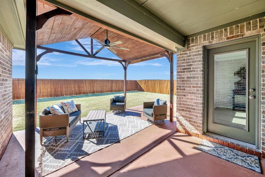 Fenced backyard featuring a patio, outdoor lounge area, and a ceiling fan