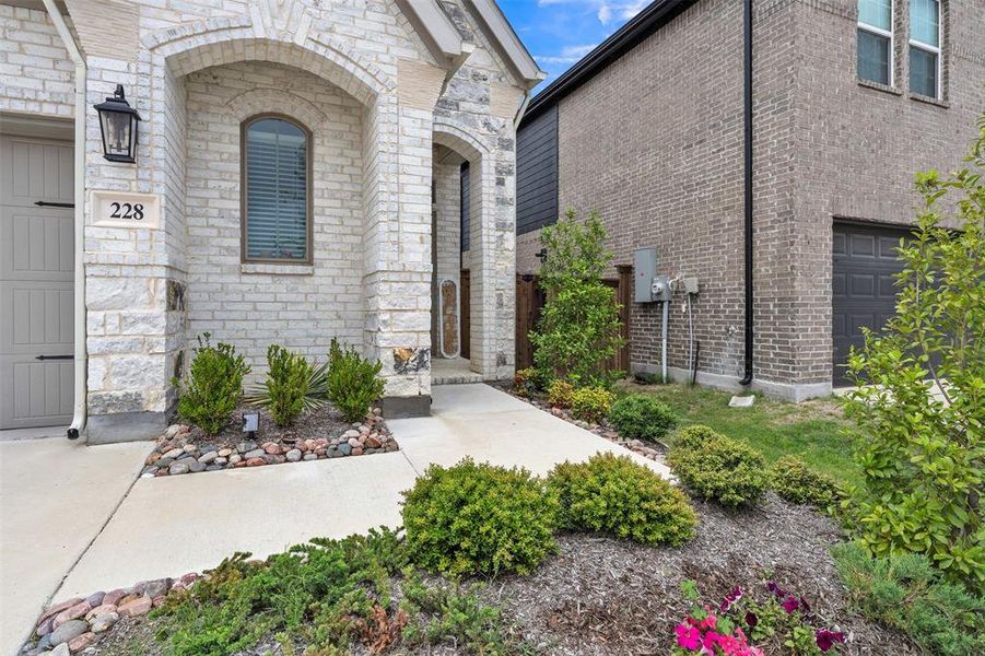 Stone and brick exterior facade with an arched entry window and accent landscaping Stone and brick exterior facade with an arched entry window and accent landscaping