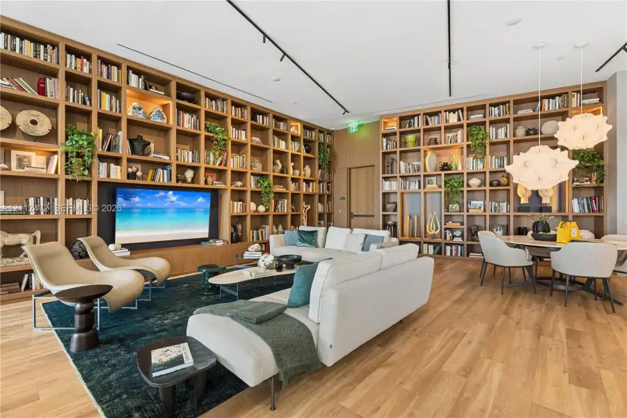 Floor-to-ceiling custom wood-finish built-in shelving, integrated accent lighting, track lighting, and wood-finish flooring