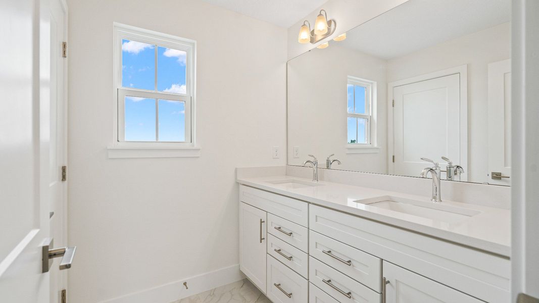 The Sweetgum secondary bathroom with dual sinks upstairs in Trailside at Mount Dora by DRB Homes