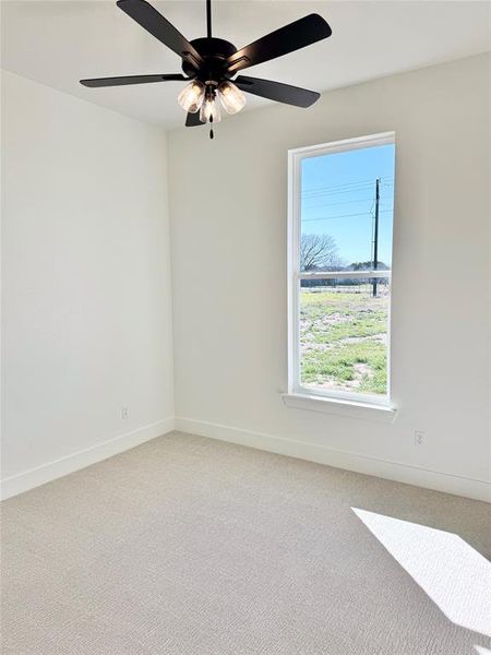 Spare room with light carpet, baseboards, and a ceiling fan