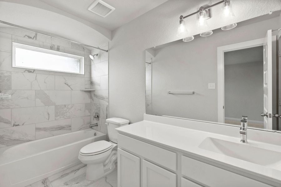 Experience sophistication in the secondary bathroom, where tile flooring complements a bath/shower combo with tile surround. Light wood cabinets complete with a beautiful light countertop, enhances the space for a truly inviting ambiance. Sample photo of completed home with similar floor plan. As-built interior colors and selections may vary.