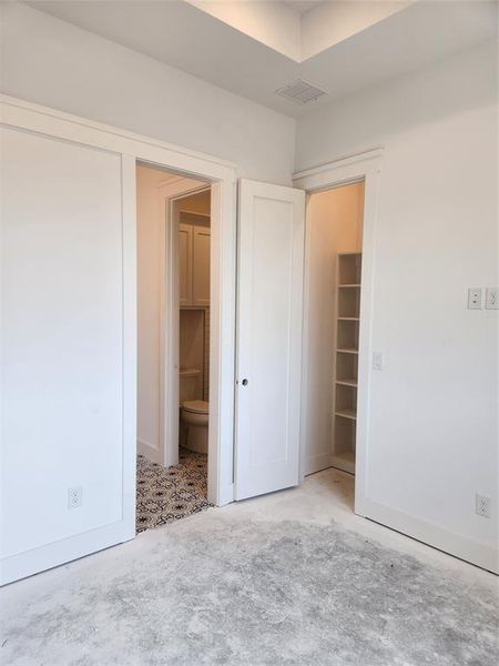 Unfurnished bedroom featuring ensuite bath and a walk in closet