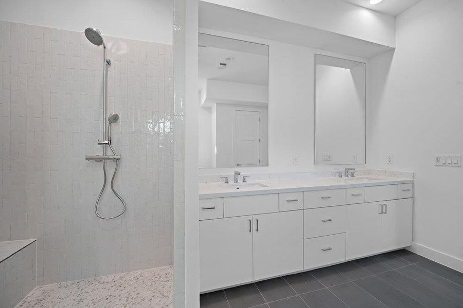 Bathroom with double vanity, a walk in shower, and dark tile patterned flooring Bathroom with double vanity, a walk in shower, and dark tile patterned flooring
