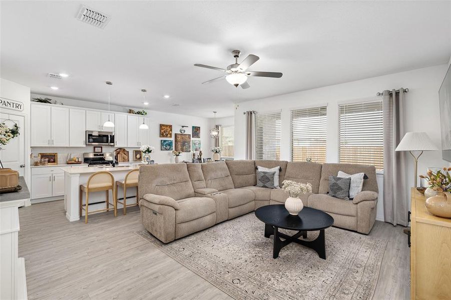 Living area featuring light wood-style flooring, white walls, and a ceiling fan