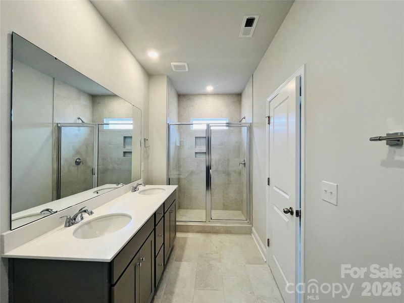 Primary bathroom with tiled shower and quartz countertops