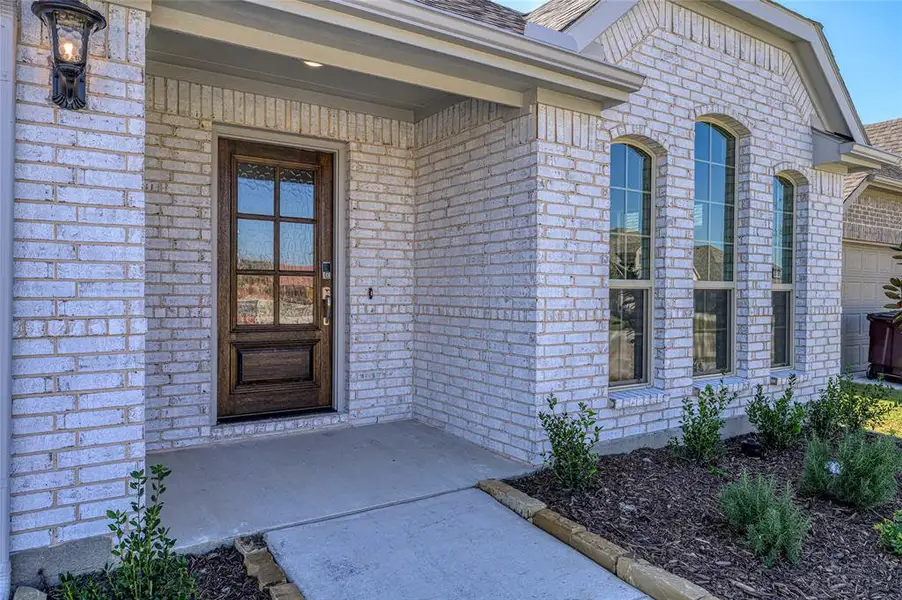 Doorway to property featuring brick siding and a shingled roof