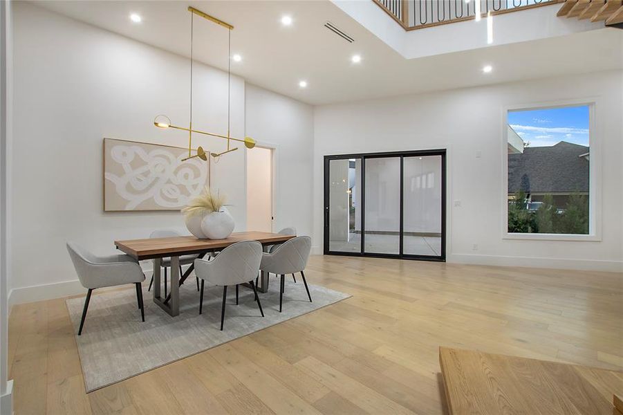 Dining area featuring a chandelier, a towering ceiling, and light hardwood / wood-style flooring