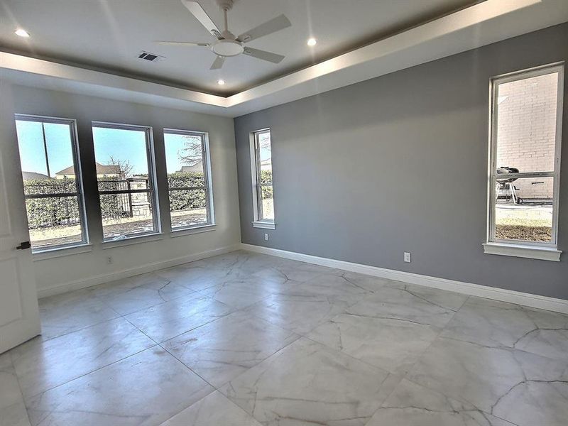 Master bedroom featuring ceiling fan and a tray ceiling