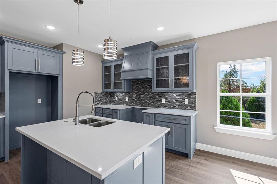 Kitchen featuring backsplash, gray cabinets, glass insert cabinets, pendant lighting, and dark wood finished floors Kitchen featuring backsplash, gray cabinets, glass insert cabinets, pendant lighting, and dark wood finished floors