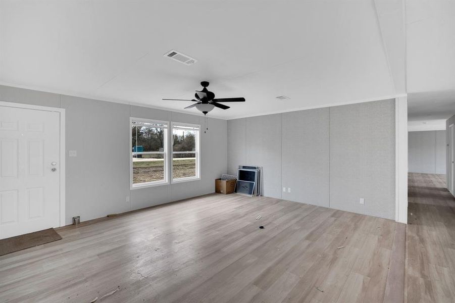 Unfurnished living room with light wood finished floors and ceiling fan