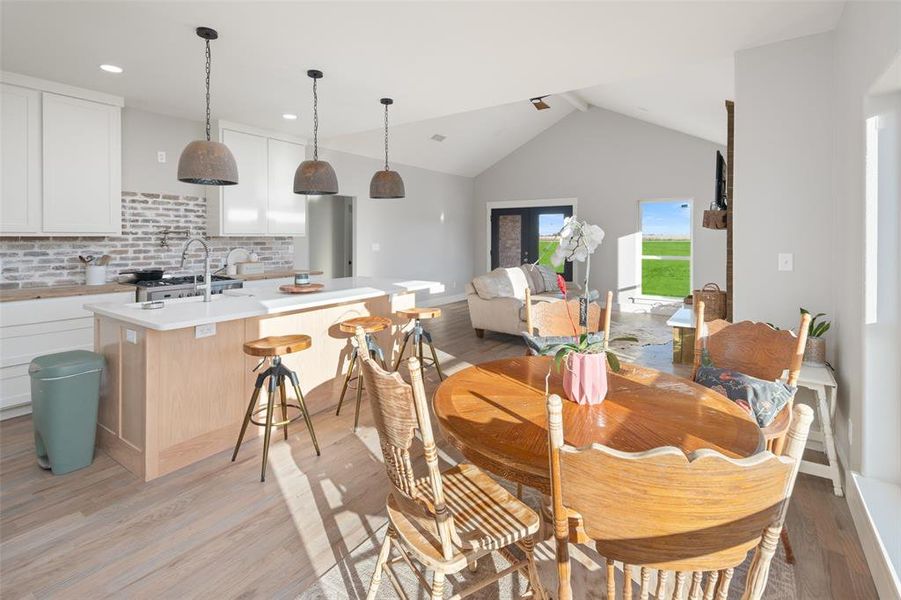 Dining room featuring french doors, vaulted ceiling, and light wood-type flooring