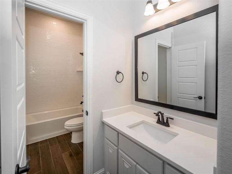 Bathroom featuring vanity, wood finish floors, and shower / tub combination