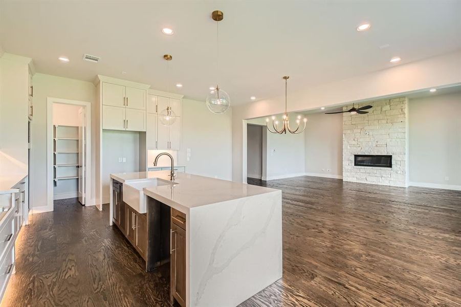 Kitchen with a fireplace, dark wood-style flooring, a ceiling fan, white cabinetry, and pendant lighting Kitchen with a fireplace, dark wood-style flooring, a ceiling fan, white cabinetry, and pendant lighting
