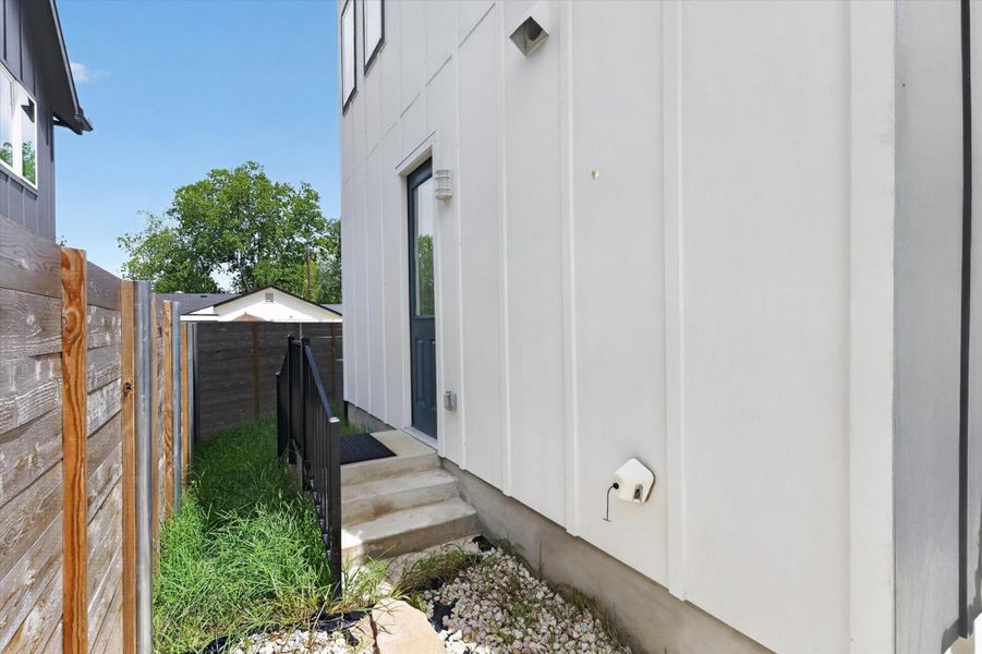 A side entrance leads to a well-maintained exterior, featuring a private fenced yard.
