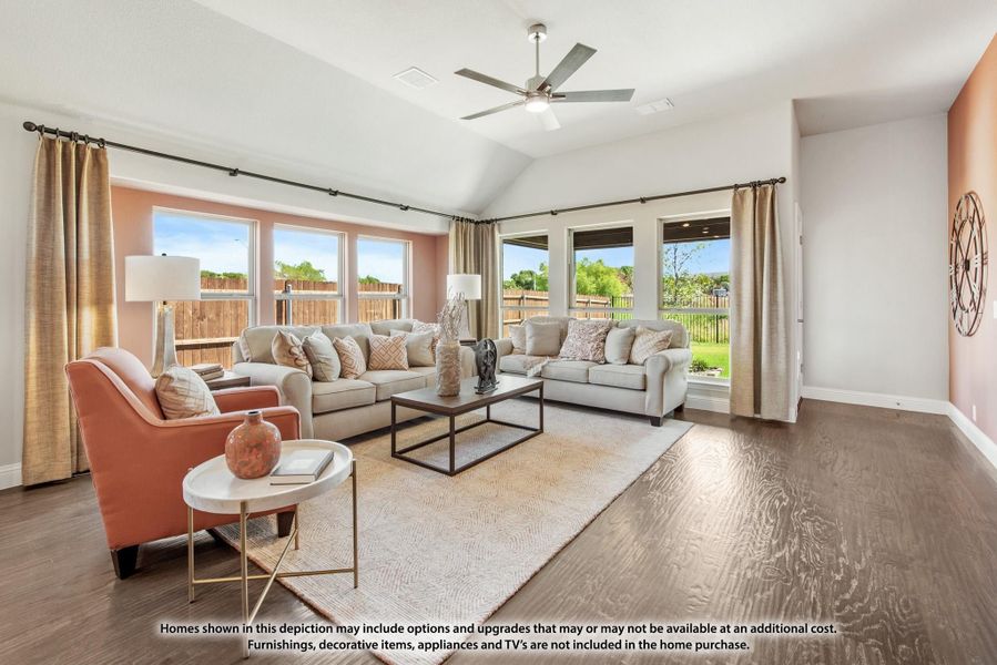Living room with vaulted ceiling, hardwood floors, ceiling fan, and large windows overlooking backyard Living room with vaulted ceiling, hardwood floors, ceiling fan, and large windows overlooking backyard