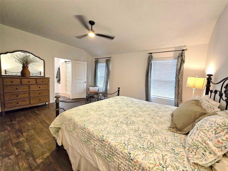 Vaulted ceiling with a ceiling fan, wood-finish flooring, window with blinds, and white interior doors