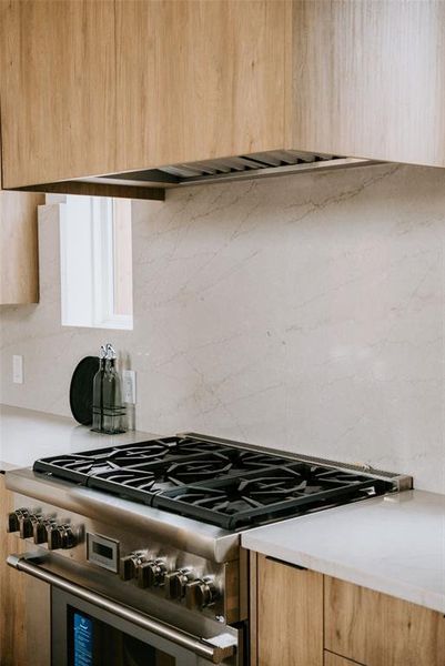 Kitchen featuring backsplash and high end stove