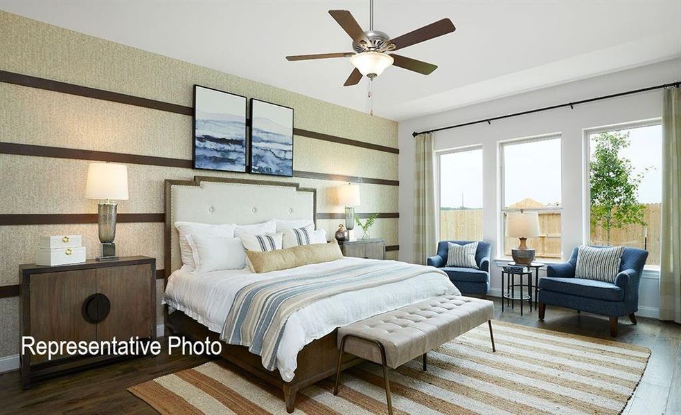 Spacious room featuring wood-finish flooring, a ceiling fan with integrated lighting, and three large windows