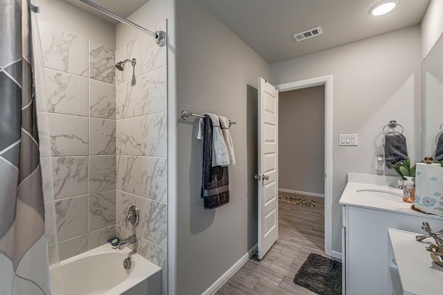 Bathroom with vanity, shower / bath combo with shower curtain, and hardwood / wood-style floors