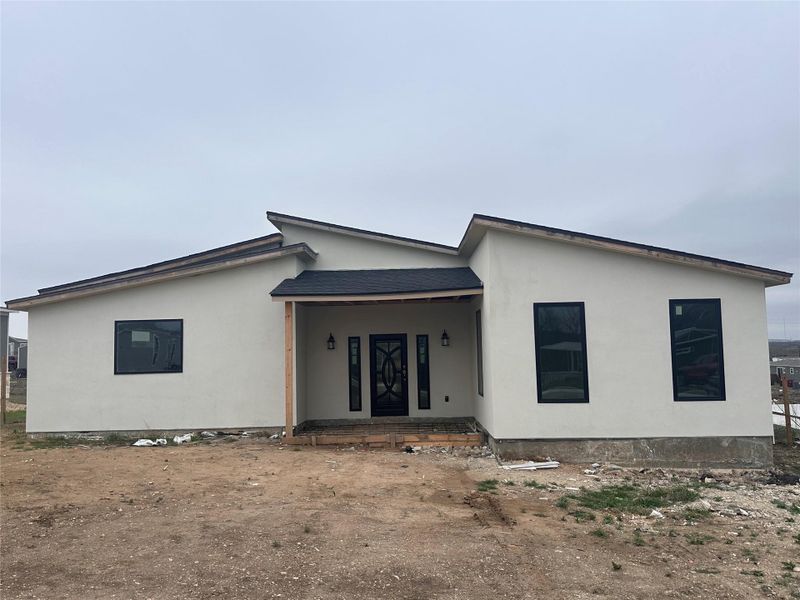 Back of house with covered porch and stucco siding