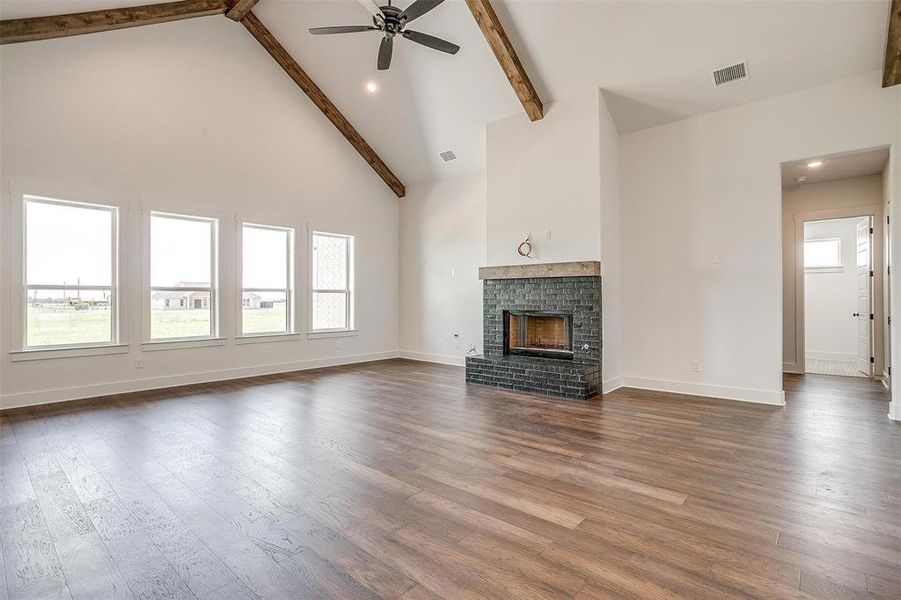 Unfurnished living room featuring a fireplace, dark wood-type flooring, and beam ceiling