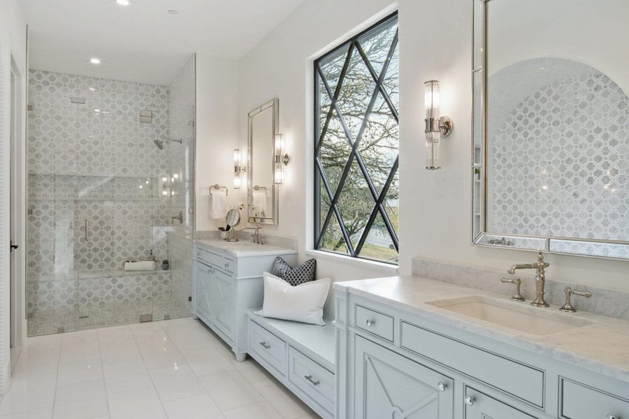 Bathroom with tile patterned flooring, two vanities, walk in shower, and a sink