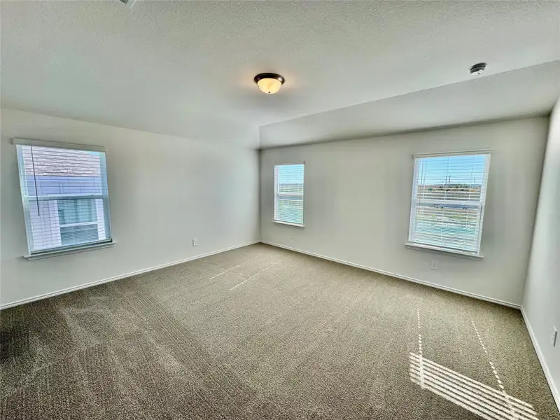 Carpeted spare room featuring a textured ceiling and baseboards