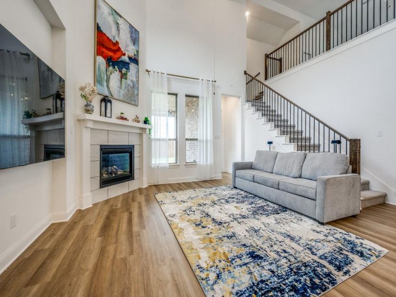 Living room featuring wood finished floors, a towering ceiling, a fireplace, and stairs