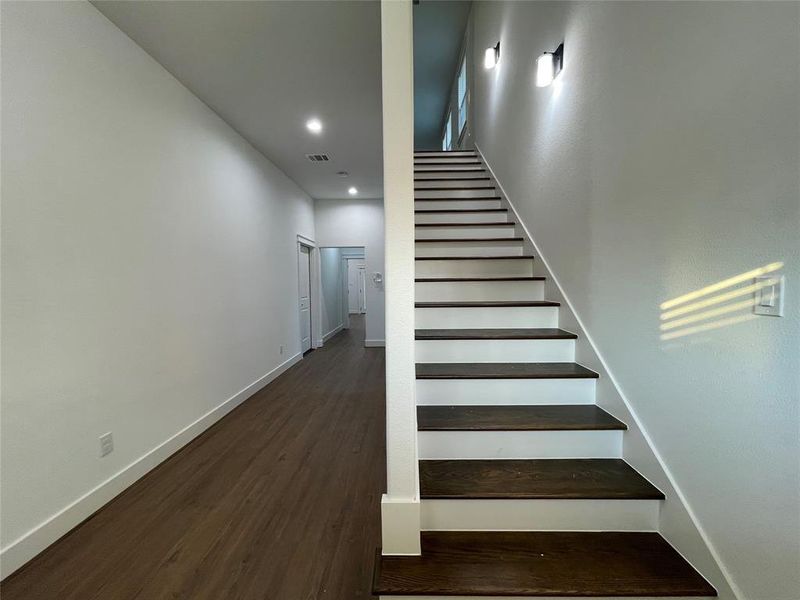 Staircase with wood finished floors and recessed lighting