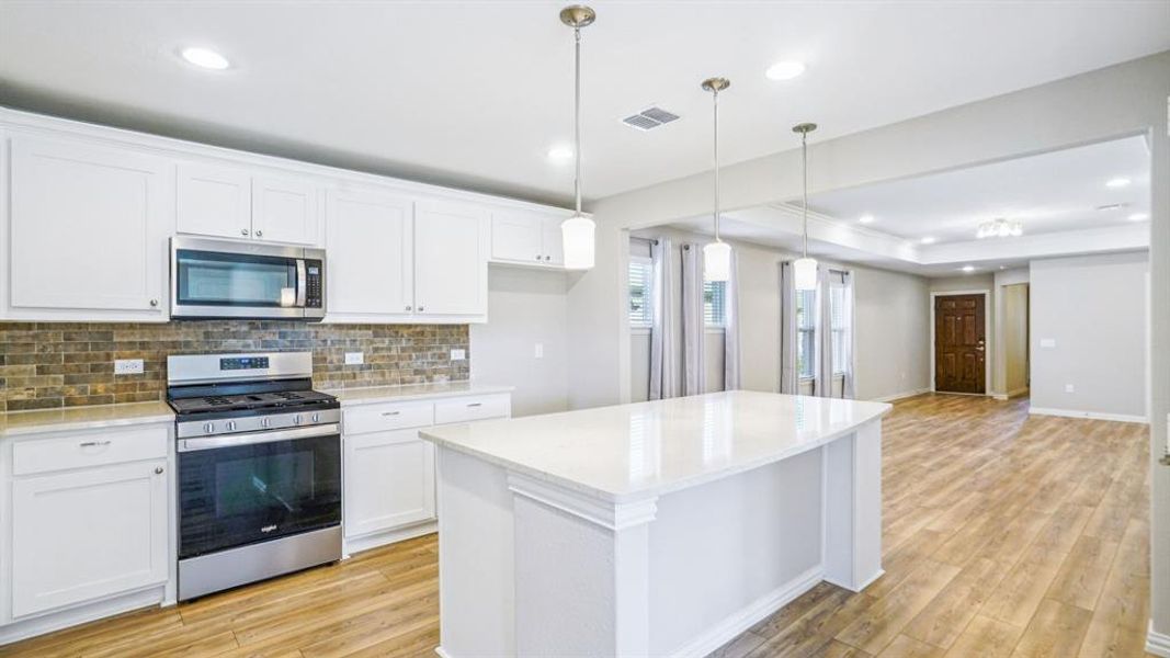 Kitchen with stainless steel appliances, white cabinets, open floor plan, pendant lighting, and a center island Kitchen with stainless steel appliances, white cabinets, open floor plan, pendant lighting, and a center island