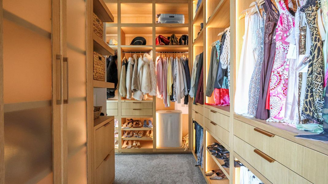 Custom cabinetry and clever lighting enhance this spacious walk-in wardrobe. Custom cabinetry and clever lighting enhance this spacious walk-in wardrobe.