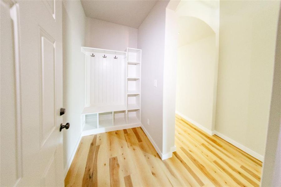 Mudroom featuring light wood finished floors and arched walkways
