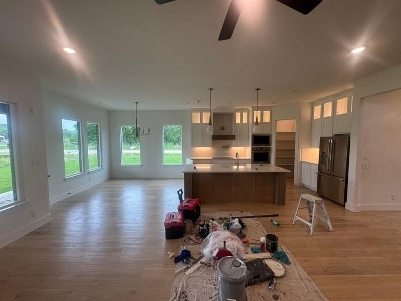 Expansive open-concept space featuring wood-finish flooring, recessed lighting, and a contemporary kitchen with a large island, stainless steel appliances, and under-cabinet lighting