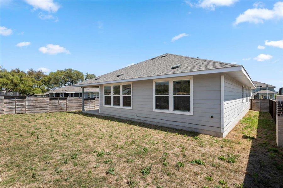 Rear view of house with a fenced backyard and roof with shingles
