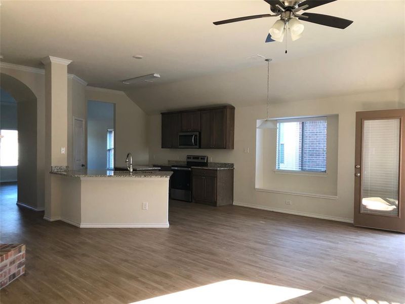 Kitchen with lofted ceiling, hardwood / wood-style flooring, light stone countertops, appliances with stainless steel finishes, and kitchen peninsula