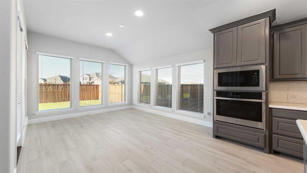 Kitchen with tasteful backsplash, stainless steel appliances, lofted ceiling, and light hardwood / wood-style floors